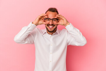 Young caucasian man with tattoos isolated on pink background  showing okay sign over eyes