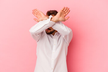 Young caucasian man with tattoos isolated on pink background keeping two arms crossed, denial concept.