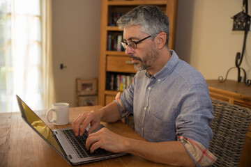 portrait d'un homme de 50 ans en train de travailler à son domicile sur son ordinateur portable