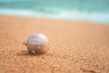 A lonely glass Christmas tree ball on the sandy seashore. Copy space.
