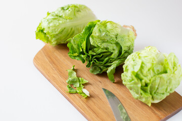 Three green fresh lettuce salads are on a cutting board on the kitchen table. Healthy food theme.
