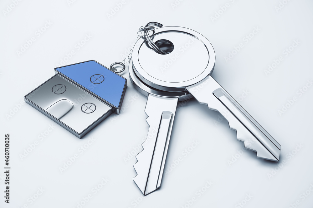 Poster close up of keys with house keychain on white surface background. real estate and property concept. 