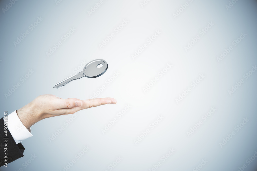 Poster close up of businessman hand holding silver key on gray background with mock up place. mortgage and 