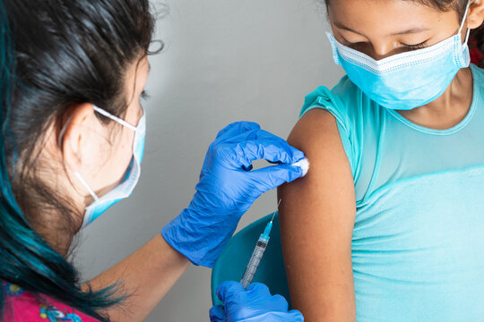 children's nurse wiping blood with cotton wool after administering injection in brown girl's arm. doctor injecting vaccine against covid-19. flu vaccine. medical concept, health and pandemic.