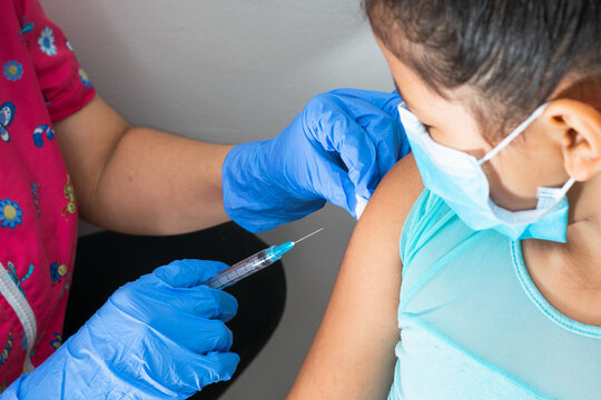 children's nurse wiping blood with cotton wool after administering injection in brown girl's arm. doctor injecting vaccine against covid-19. flu vaccine. medical concept, health and pandemic.