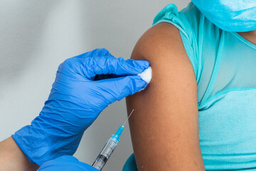 children's nurse wiping blood with cotton wool after administering injection in brown girl's arm. doctor injecting vaccine against covid-19. flu vaccine. medical concept, health and pandemic.