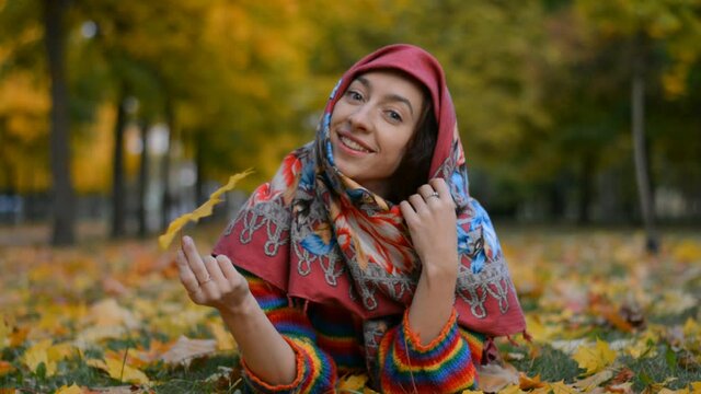 Beautiful and happy Russian girl smiling portrait in autumn park lies on the grass