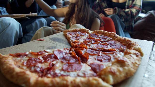 Young hipsters are sharing pepperoni pizza in a dance studio 
