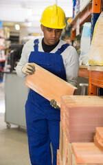 Worker in overalls transports thermal insulation panels at a hardware store warehouse