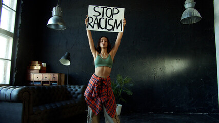 Young brunette is holding protest banner demanding stop racism 