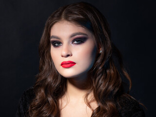 Gorgeous young brunette in a chic evening look. Scarlet lips and eye shadow, wave hair styling....