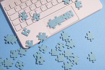 Puzzle elements on a laptop keyboard, software development, concept. Mosaic on a blue background