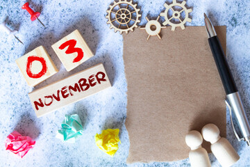 November 3. Date of November month. Number Cube with a flower and notebook on Diamond wood table for the background