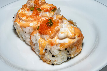 Spicy shrimp roll on rice ball topped with salad cream and salmon roe.