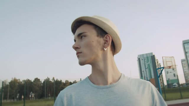 Portrait of a guy with a hat and earring in his ear against a street background
