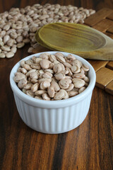 Pinto beans. Beans inside a ramekin on a rustic table. Wooden spoon in the background. Typical ingredient. Brazilian food. Vertical orientation.