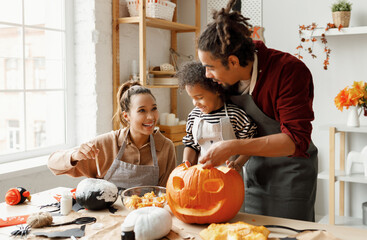 Joyful african american family mother, father and boy son enjoying Halloween preparation at home