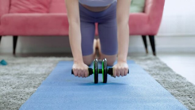 closed up,Asian Sporty Woman is using Roller abs wheel exercise machine to build abdominal and back muscles, fitness concept and wellness.
