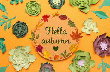 Creative paper flowers and card with text HELLO AUTUMN on orange background