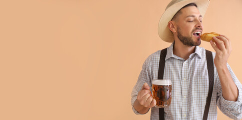 Young man in traditional German clothes with beer eating pretzel on beige background with space for text