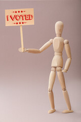 Wooden mannequin and placard with text I VOTED on grey background