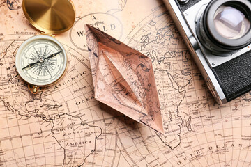 Paper boat, compass, photo camera and world map, closeup
