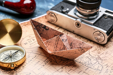 Fototapeta na wymiar Paper boat, compass, photo camera and world map on color background, closeup