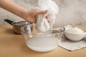 Woman preparing tasty rice milk on kitchen table, closeup