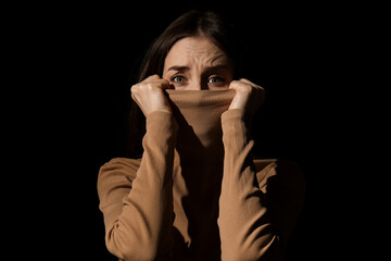 Scared young woman on dark background. Concept of harassment