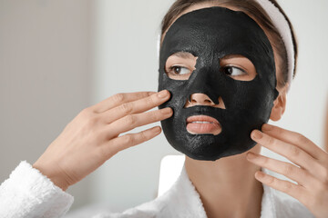 Beautiful young woman with sheet facial mask at home