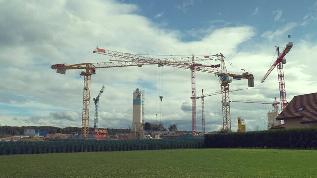 Cranes work on building houses for Osiris eco neighborhood at Echallens, city of Gros de Vaud in Switzerland. Time-lapse