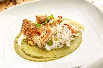 Plate with healthy baked cod fillet, rice and guacamole sauce on color background, closeup