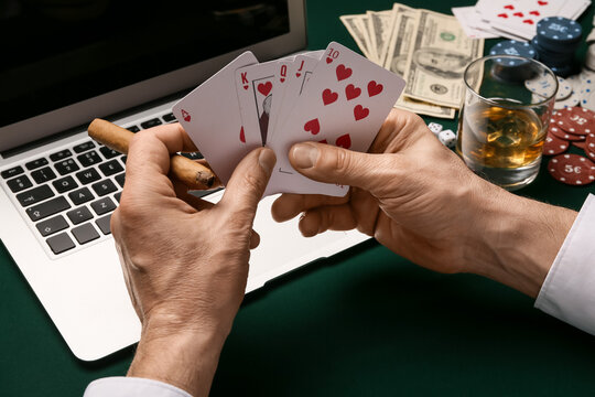 Man with laptop playing poker online at table in casino