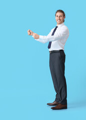 Young man with imaginary steering wheel on color background