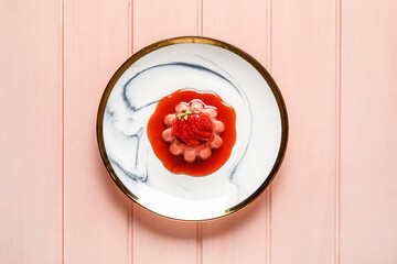 Delicious homemade strawberry panna cotta in plate on color wooden background