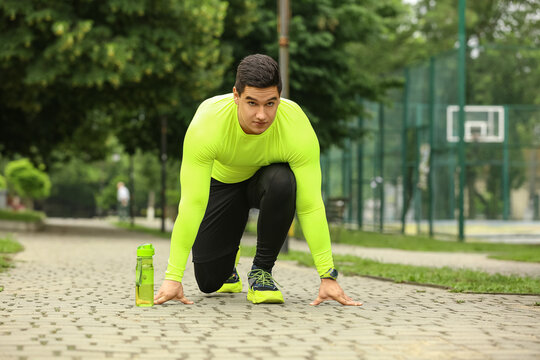 Muscular young man getting ready to run in park