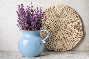 Jug with beautiful lavender flowers on light background