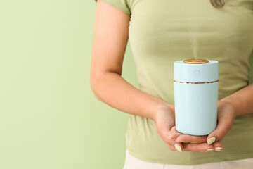 Fototapeta na wymiar Woman with modern air humidifier on color background
