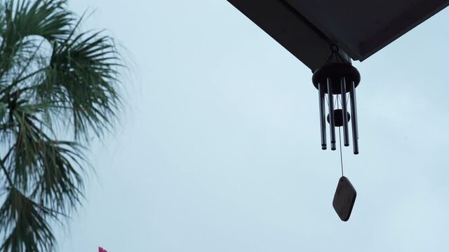 Calming and relaxing view of a wind chime blowing in a tropical garden while it's raining (moody shot)