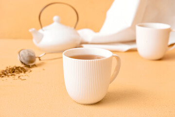Cups of tasty hojicha green tea on beige background