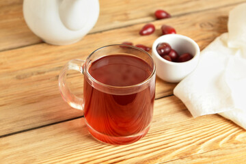 Glass cup of fresh dogwood drink on wooden background