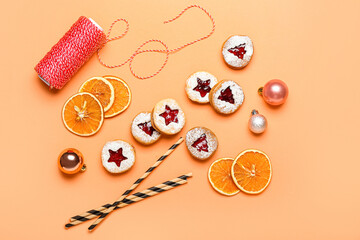 Tasty Linzer cookies with Christmas decor on color background