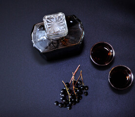 Bird cherry liqueur, a glass decanter and two glasses with an alcoholic drink on a black...