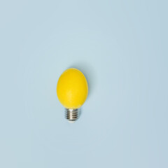 Yellow Easter egg electric lamp on a blue background. A creative idea. Minimal flat lay.