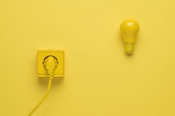 An electric cord inserted into an outlet and a light bulb on a yellow background.