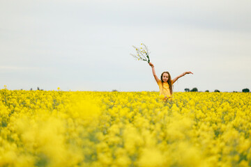 Pretty long haired girl playing in vibrant canola field in full bloom