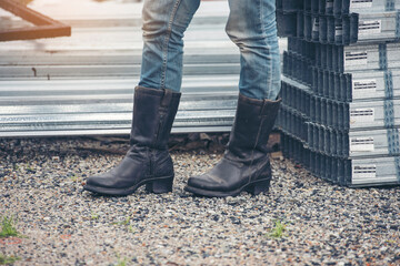 Women wear construction Boots safety footwear for worker at construction site. Woman Engineer Wear Jeans black Boots Worker standing at construction site. Engineer safety industry footwear walking