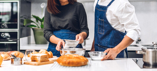 Obraz na płótnie Canvas Young asian family couple having fun cooking together with dough for homemade bake cookie and cake ingredient on table.Happy couple looking to preparing food the dough in kitchen