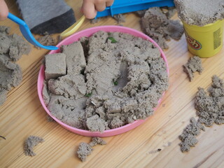 the hands of a toddler playing with kinetic sand