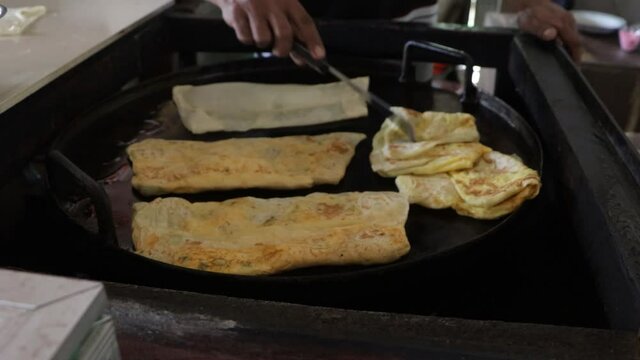 The Seller Of Roti Canai Or Roti Maryam Is Cooking By Frying On A Frying Pan